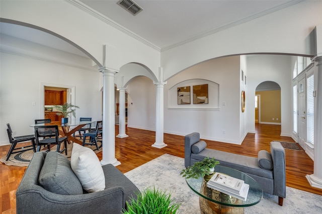 living room featuring arched walkways, wood finished floors, visible vents, and ornate columns