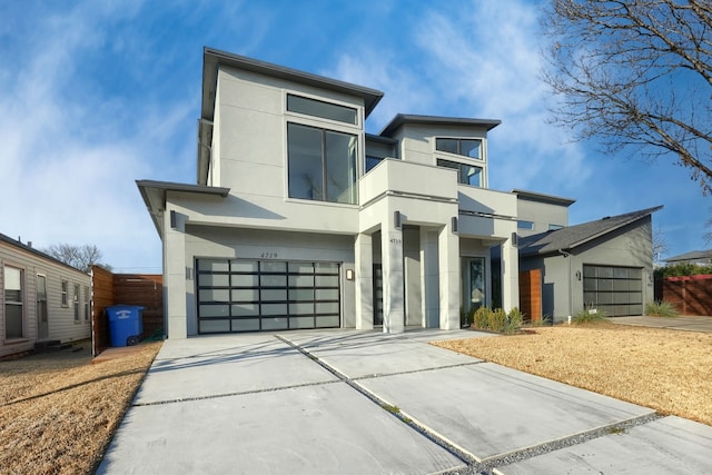 contemporary house featuring a balcony, an attached garage, concrete driveway, and stucco siding