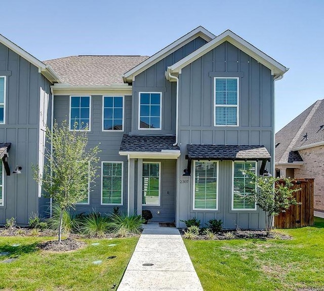 view of front facade featuring a front lawn, board and batten siding, and a shingled roof