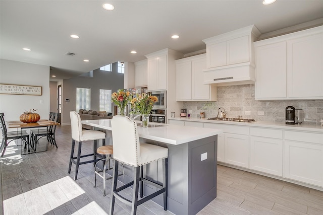 kitchen with a breakfast bar area, visible vents, appliances with stainless steel finishes, light wood finished floors, and tasteful backsplash