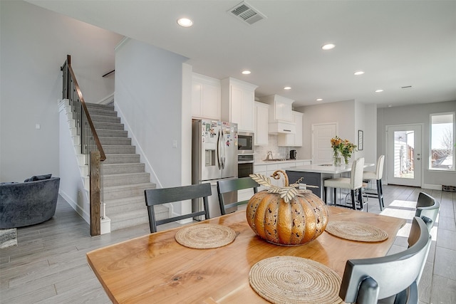 dining area with light wood-type flooring, visible vents, recessed lighting, and stairs