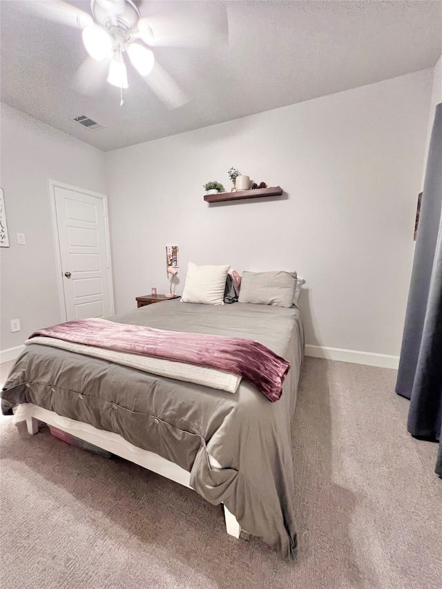 carpeted bedroom with a textured ceiling, a ceiling fan, visible vents, and baseboards