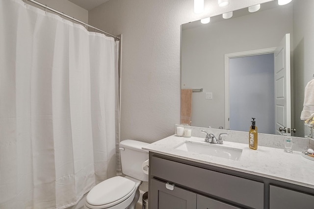 bathroom with a textured wall, a shower with shower curtain, vanity, and toilet