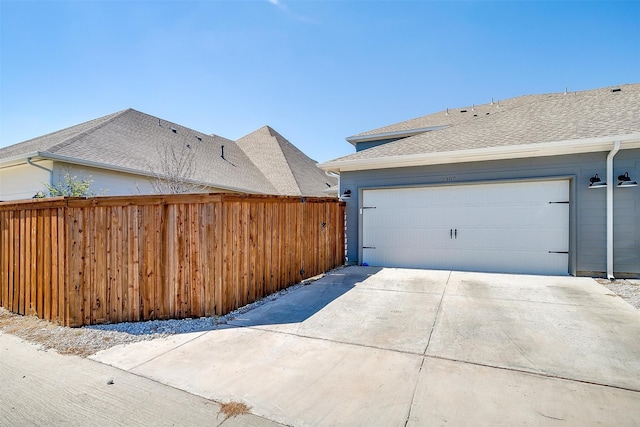 exterior space with driveway, a shingled roof, and fence