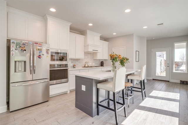 kitchen with appliances with stainless steel finishes, light wood-style flooring, visible vents, and decorative backsplash