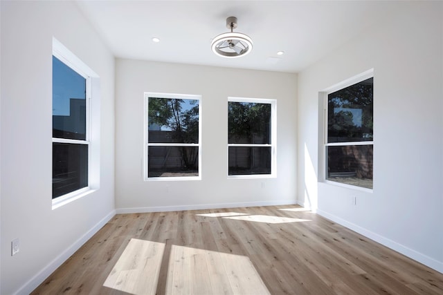 empty room with baseboards, wood finished floors, and recessed lighting