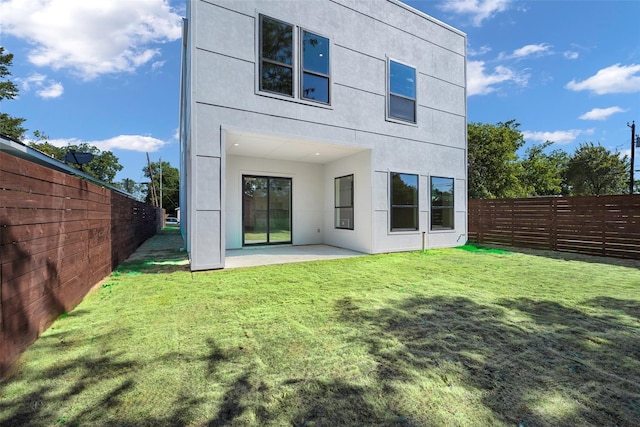 rear view of property featuring a patio, a lawn, a fenced backyard, and stucco siding