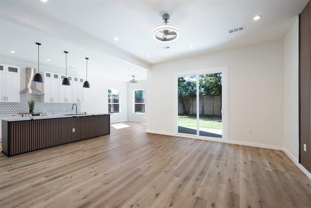 kitchen featuring tasteful backsplash, a spacious island, visible vents, open floor plan, and wall chimney range hood