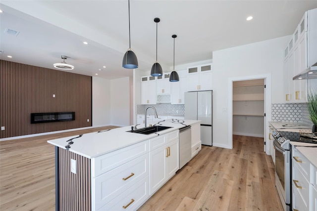 kitchen featuring a sink, visible vents, appliances with stainless steel finishes, light wood-type flooring, and glass insert cabinets