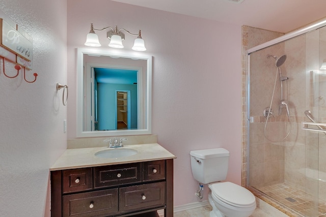 bathroom featuring vanity, a shower stall, toilet, and baseboards