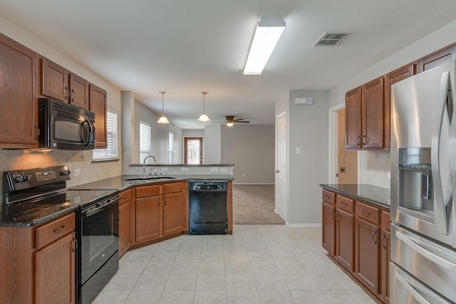 kitchen with visible vents, brown cabinetry, a peninsula, black appliances, and a sink