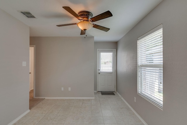 spare room featuring a ceiling fan, visible vents, and baseboards