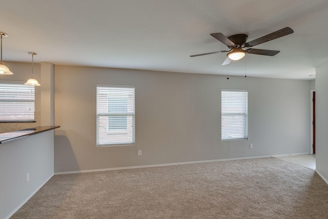 carpeted empty room featuring baseboards, a ceiling fan, and a healthy amount of sunlight