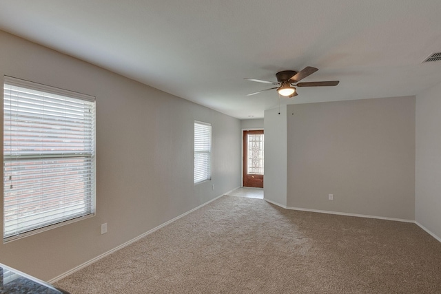 empty room with light carpet, baseboards, visible vents, and a ceiling fan