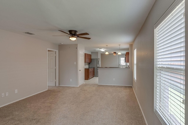 unfurnished living room with ceiling fan, baseboards, visible vents, and light colored carpet