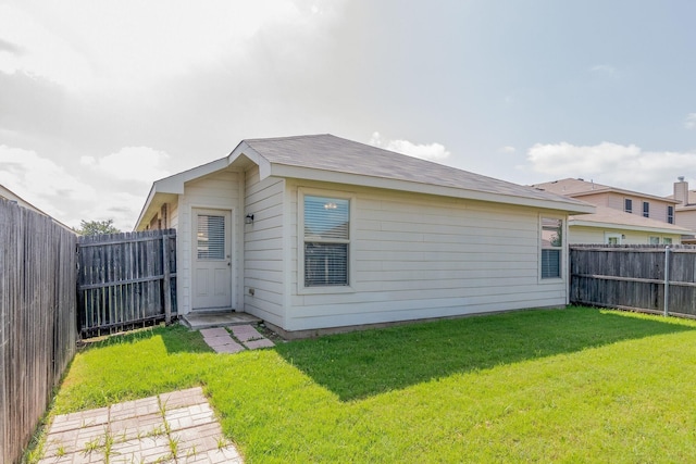 rear view of house with a lawn and a fenced backyard