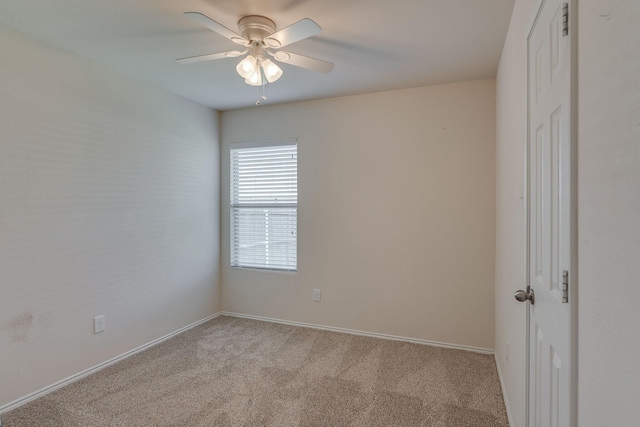 carpeted empty room featuring a ceiling fan and baseboards