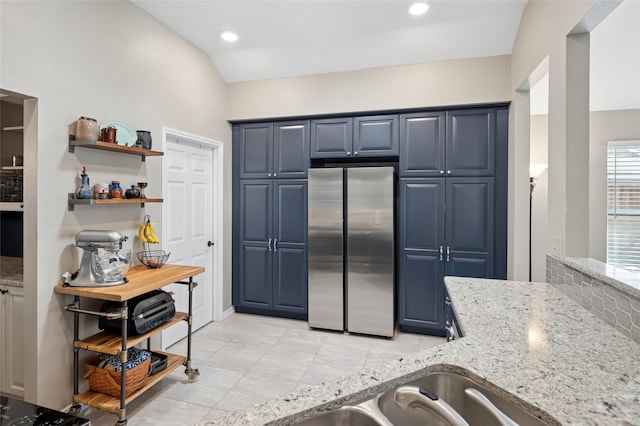 kitchen featuring light tile patterned flooring, blue cabinets, recessed lighting, freestanding refrigerator, and light stone countertops