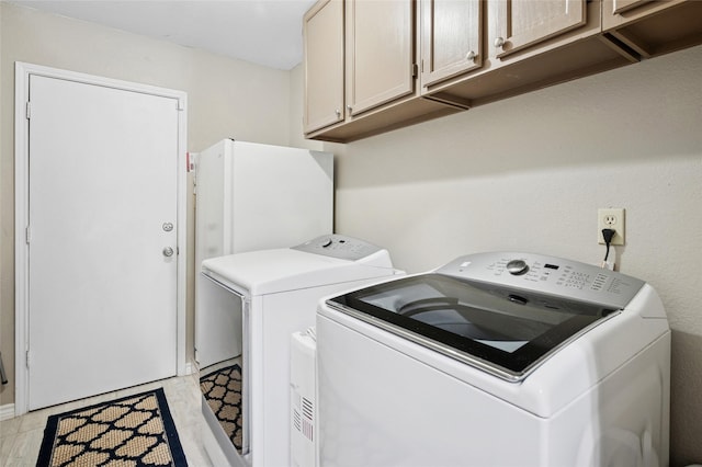 clothes washing area featuring cabinet space and washing machine and dryer