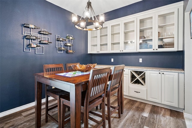 dining space featuring dark wood-style flooring, baseboards, and an inviting chandelier