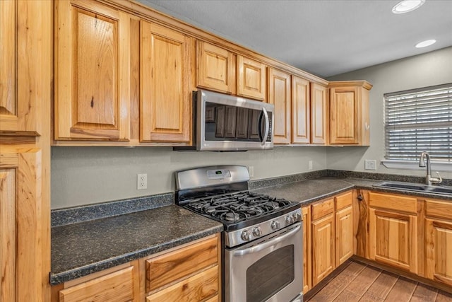 kitchen featuring stainless steel appliances, dark countertops, and a sink