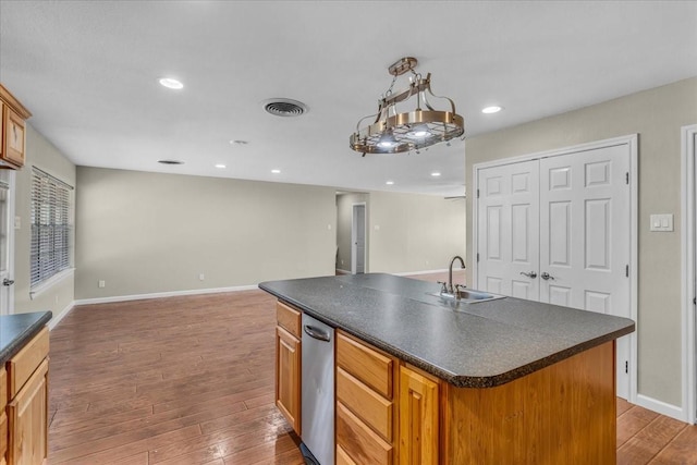 kitchen featuring hardwood / wood-style floors, dark countertops, a sink, and visible vents