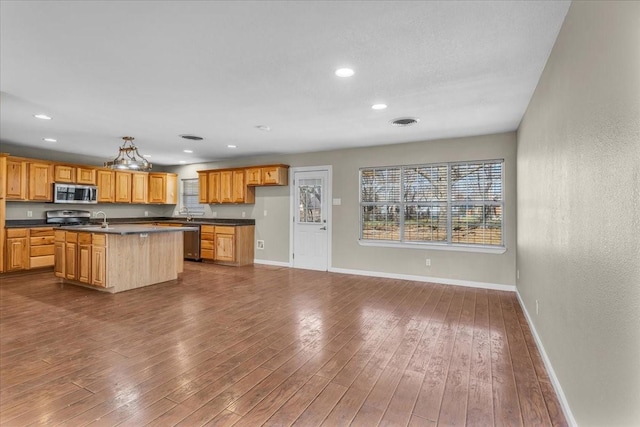 kitchen featuring dark wood-style floors, stainless steel appliances, and dark countertops