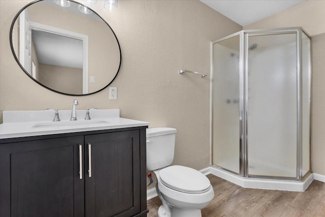 full bathroom with toilet, wood finished floors, vanity, baseboards, and a stall shower