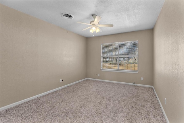 carpeted empty room with visible vents, a textured wall, a ceiling fan, a textured ceiling, and baseboards