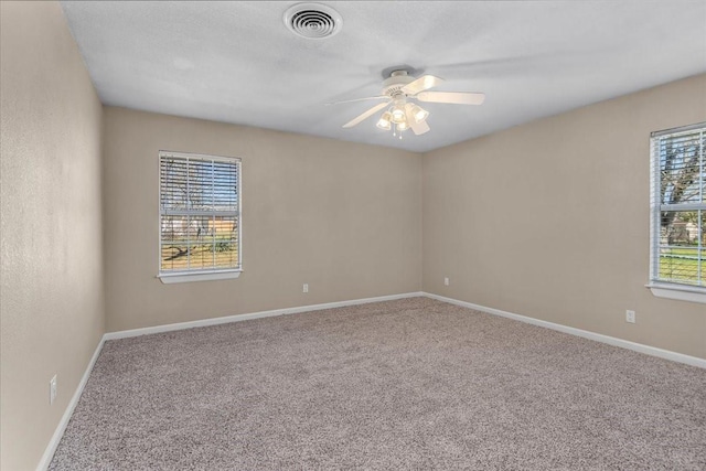 carpeted empty room featuring baseboards, visible vents, and a ceiling fan