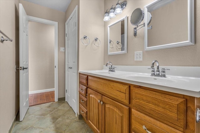 full bath with double vanity, baseboards, and a sink