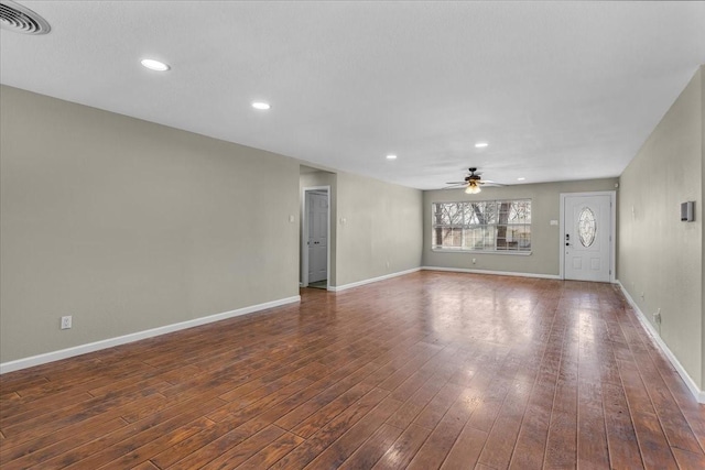 unfurnished living room featuring a ceiling fan, visible vents, dark wood finished floors, and baseboards