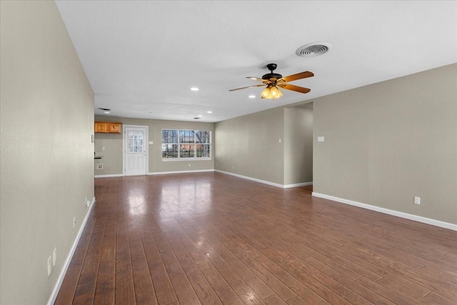 unfurnished living room with baseboards, visible vents, ceiling fan, and dark wood-style flooring