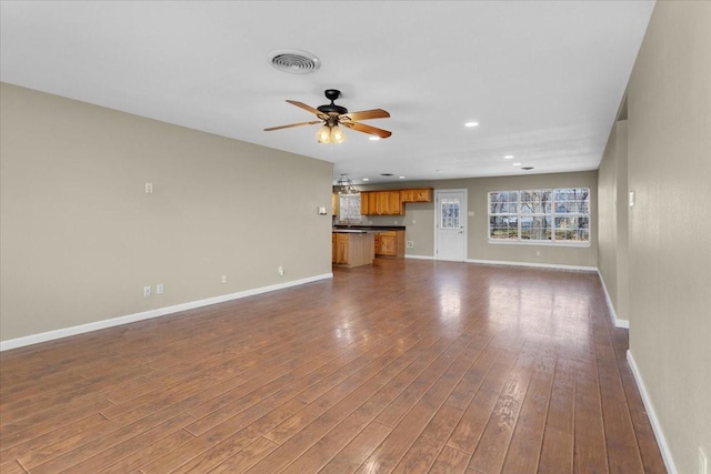 unfurnished living room with ceiling fan, dark wood finished floors, visible vents, and baseboards