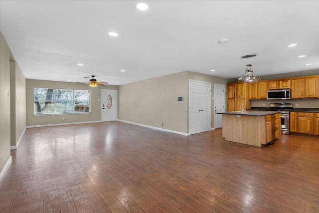 kitchen featuring stainless steel appliances, dark countertops, dark wood-style flooring, and open floor plan