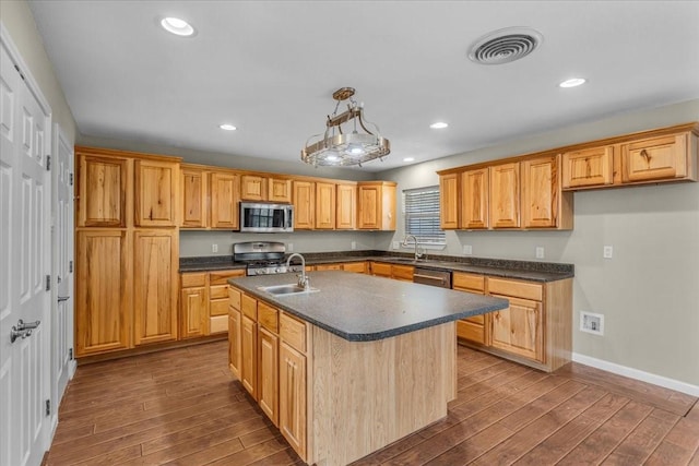 kitchen with visible vents, dark countertops, appliances with stainless steel finishes, dark wood-type flooring, and a sink