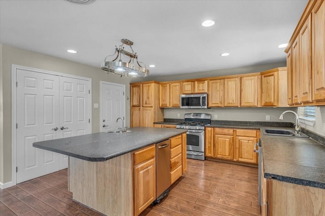 kitchen featuring appliances with stainless steel finishes, dark countertops, a sink, and wood-type flooring