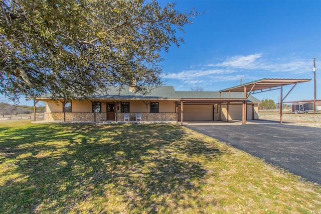 ranch-style house featuring a carport, a front yard, stone siding, and driveway