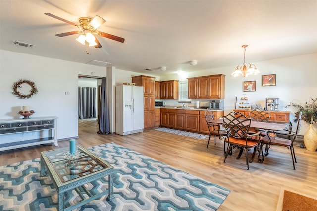 dining room featuring visible vents, light wood finished floors, and ceiling fan with notable chandelier