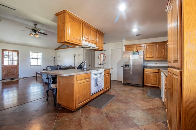 kitchen featuring brown cabinetry, white appliances, visible vents, and open floor plan