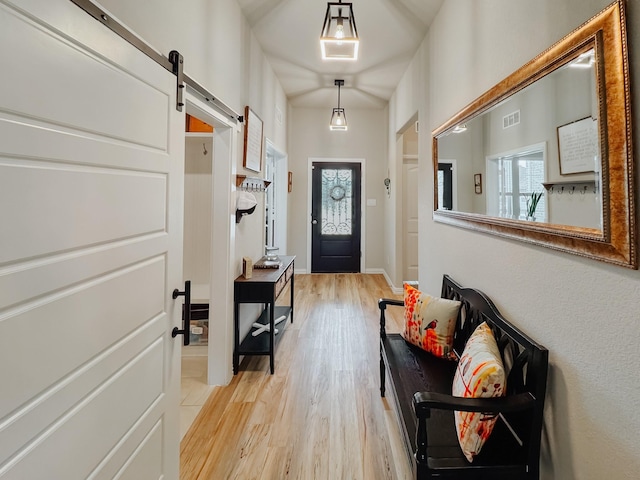 doorway with a barn door, light wood-style flooring, visible vents, and baseboards