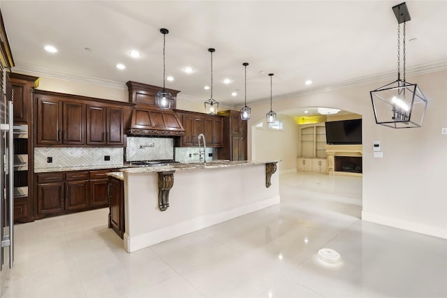 kitchen featuring a fireplace, a breakfast bar area, custom exhaust hood, stainless steel double oven, and open floor plan