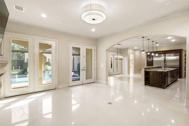 interior space featuring arched walkways, visible vents, baseboards, french doors, and ornamental molding