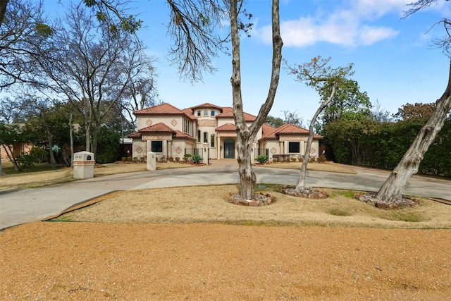 mediterranean / spanish-style house featuring a tile roof, concrete driveway, and stucco siding