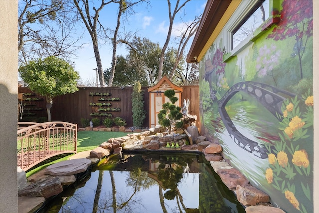 view of yard featuring a fenced backyard and a small pond