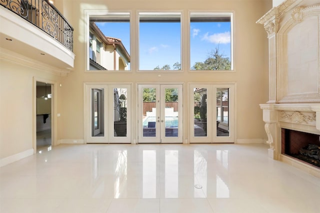 unfurnished living room featuring tile patterned floors, a towering ceiling, and baseboards