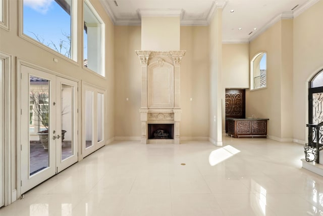 unfurnished living room featuring ornamental molding, a high end fireplace, baseboards, and a high ceiling