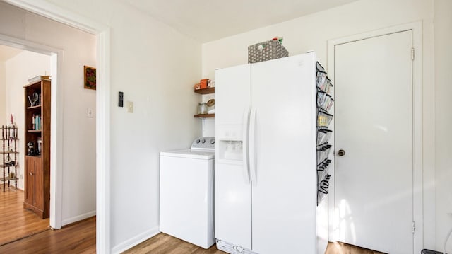 laundry room featuring laundry area, baseboards, light wood-style floors, and washer / dryer