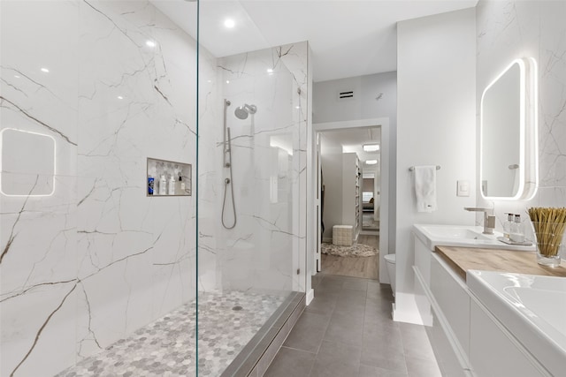 full bathroom featuring connected bathroom, toilet, a sink, a marble finish shower, and double vanity