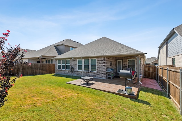 back of house with a fenced backyard, brick siding, a yard, roof with shingles, and a patio area